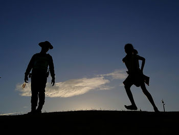 Low angle view of silhouette man standing on field against sky