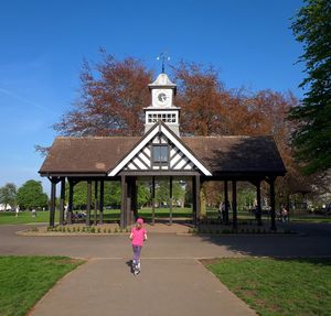 Rear view of woman riding bicycle on footpath against sky