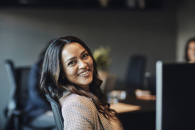 Side view portrait of smiling businesswoman sitting in office