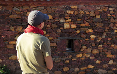 Rear view of man standing against brick wall