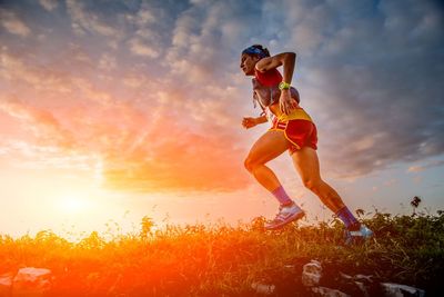 Low angle view of woman on field against sky during sunset