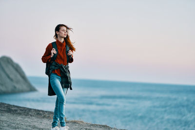 Young woman standing in sea against sky