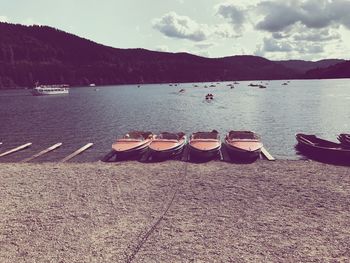 Sailboats moored on lake against sky