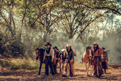 People walking with horses in forest