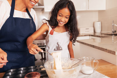 Portrait of young woman preparing food in kitchen