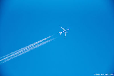 Low angle view of vapor trail against blue sky