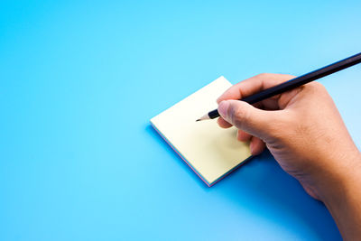 Midsection of person reading book against blue background