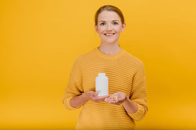 Portrait of smiling young woman against yellow background