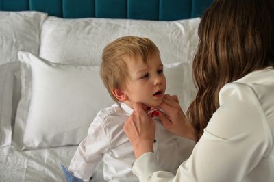 Mother with her toddler while putting on clothes for his birthday