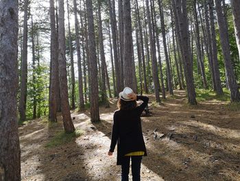 Full length of woman standing amidst trees in forest