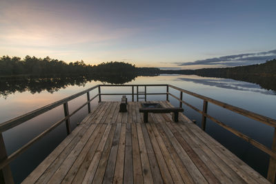 Pier over lake against sky during sunset