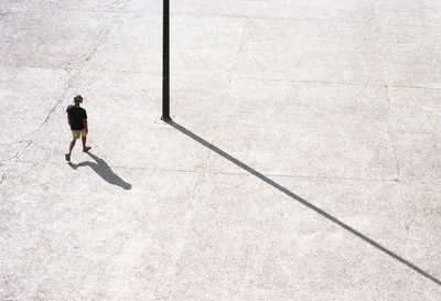 High angle view of man walking with shadow on footpath