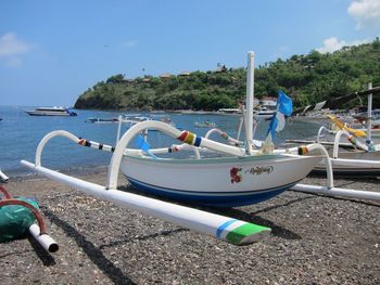 Man moored at sea shore against blue sky