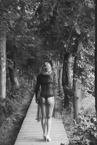 Rear view of woman walking on footpath in forest