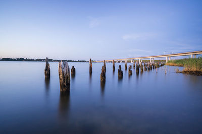 Wooden posts in lake against sky