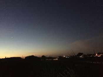 Silhouette trees on field against sky at night