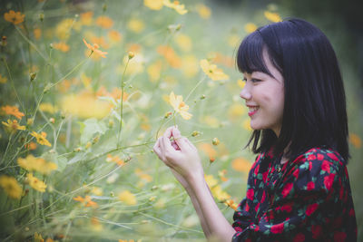 Young woman looking down while standing on flowering plant