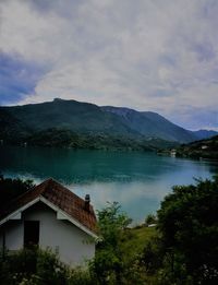 House by lake and mountains against sky