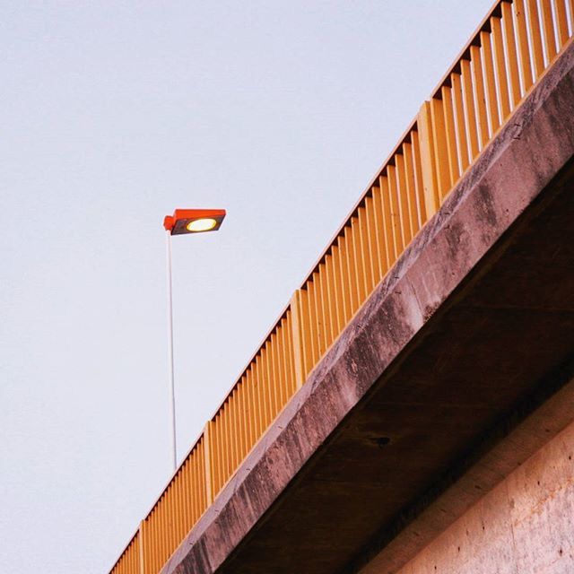 clear sky, low angle view, architecture, built structure, copy space, building exterior, street light, lighting equipment, red, no people, outdoors, building, wall - building feature, day, railing, city, high section, flag, blue, pole