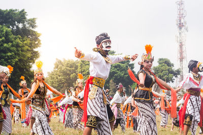 Group of people dancing against sky