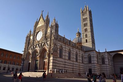 People at temple against clear blue sky
