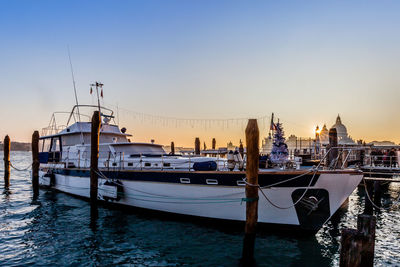 Boats moored in river at sunset