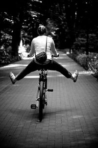 Rear view of woman riding bicycle on footpath