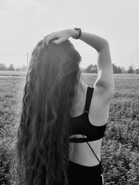 Rear view of woman with arms raised standing in background