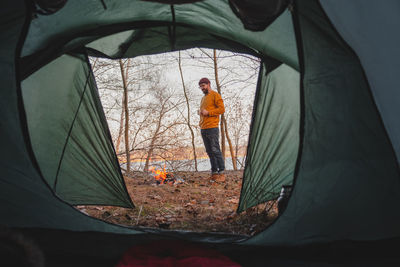 Man standing by bonfire in forest