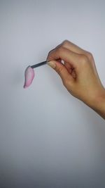 Close-up of woman holding petal over white background