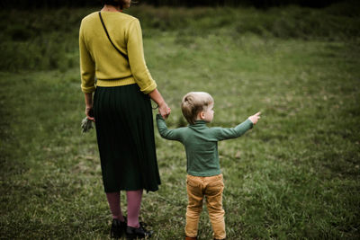 Anonymous mother and her son walking together in the forest.