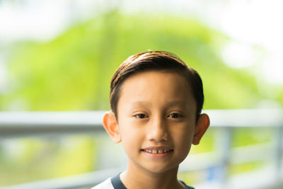 Close-up portrait of boy smiling against railing