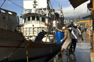 Rear view of people standing on boats moored in canal