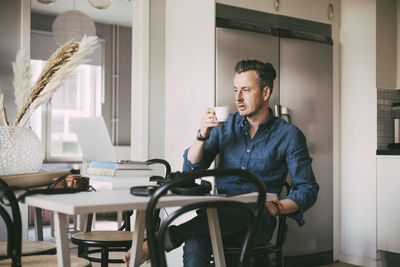 Man having a coffee in kitchen working at home
