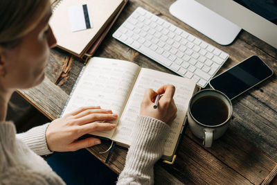 Woman plans work by marking the date on the calendar while sitting in the office.