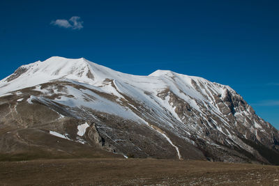 Scenic view of snowcapped mountains against blue sky