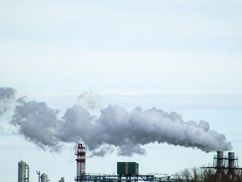 Smoke emitting from factory against sky