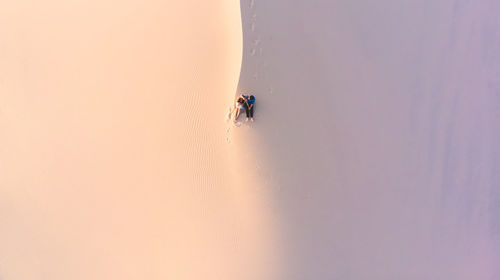 High angle view of couple sitting on sand at desert