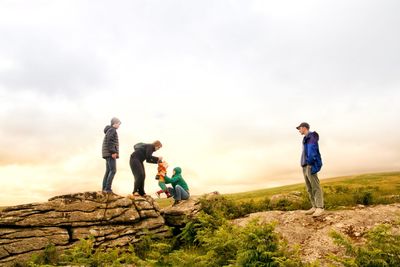 People standing on rock against sky