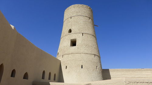 Low angle view of tower at bahla fort against clear sky