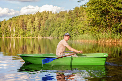 Man in boat on lake against trees