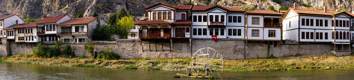 Houses by river against buildings