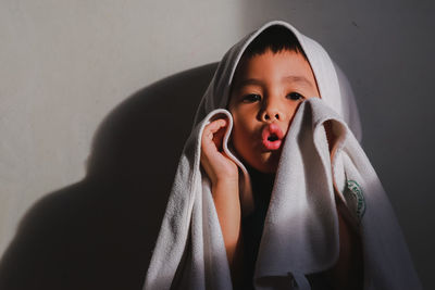 Portrait of boy wrapped in towel against wall