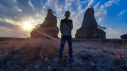 Man standing on rock against sky