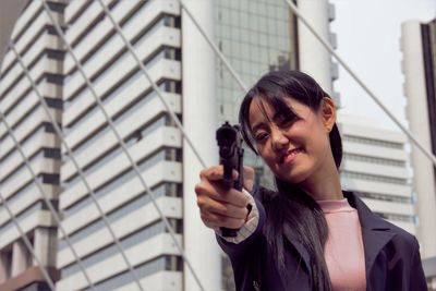 Close-up of woman pointing pistol at camera