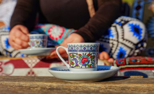 Midsection of woman holding drink sitting on table