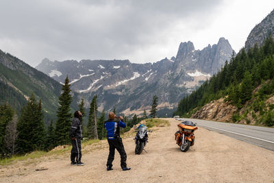 People riding motorcycle on mountain road against sky