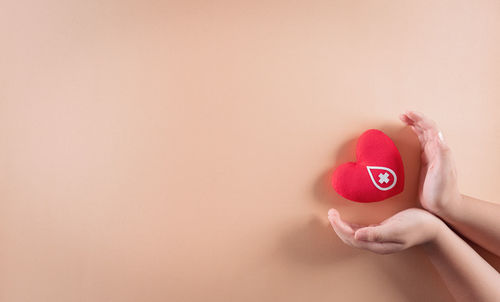 Close-up of woman holding heart shape over white background