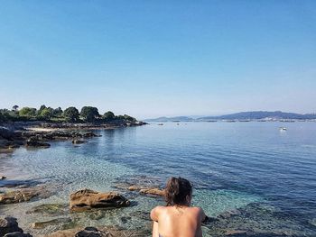 Low section of person on beach against clear blue sky