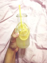 Hand holding bottle of lemonade at home